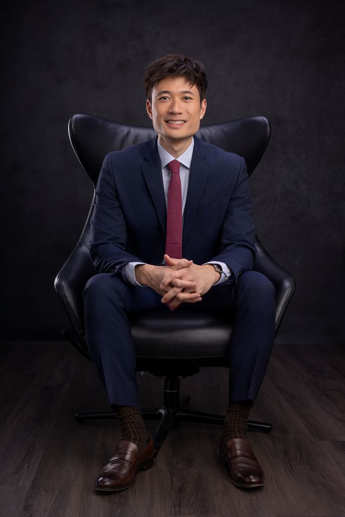 Dr. Jonathan Dang wearing suit with red tie sitting in chair